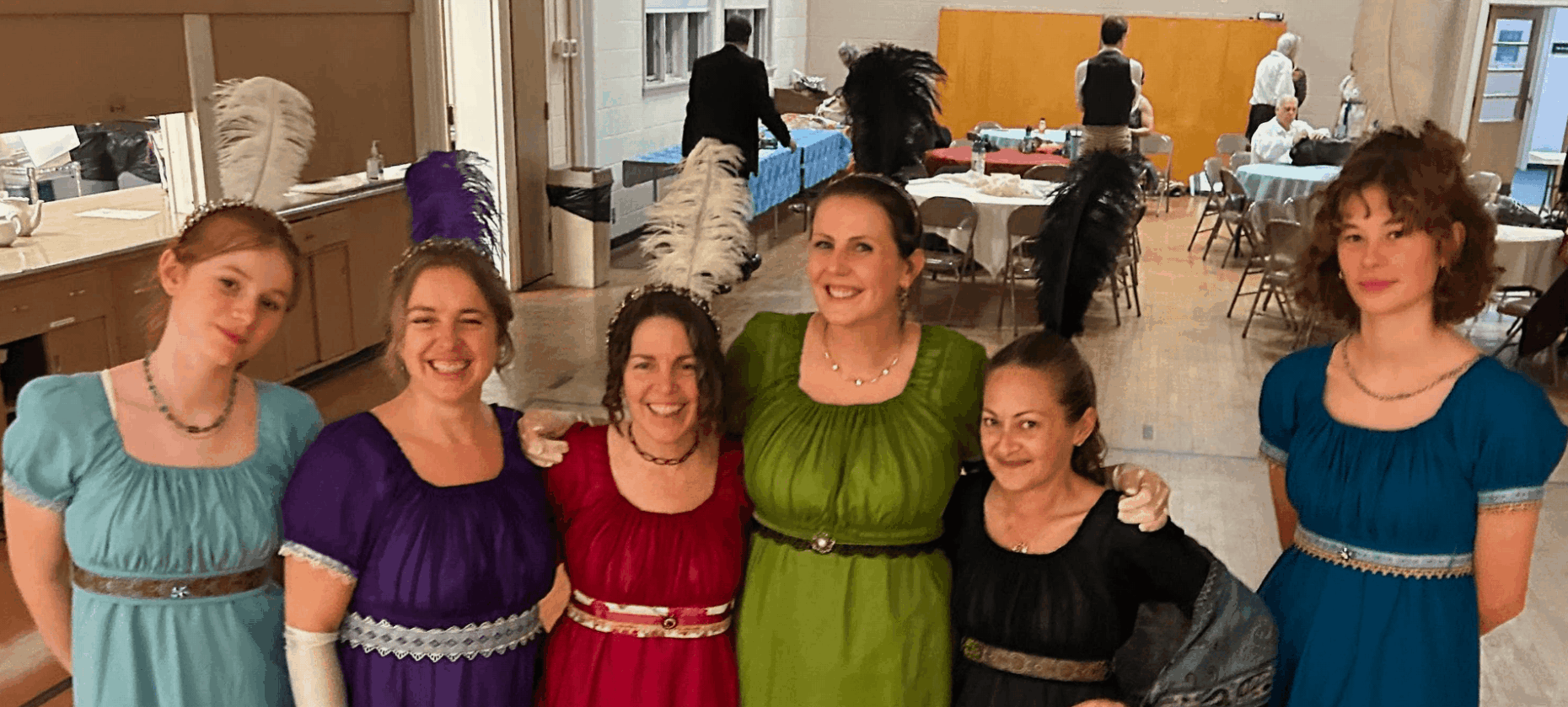 6 women in Regency gowns with feathers in their hair