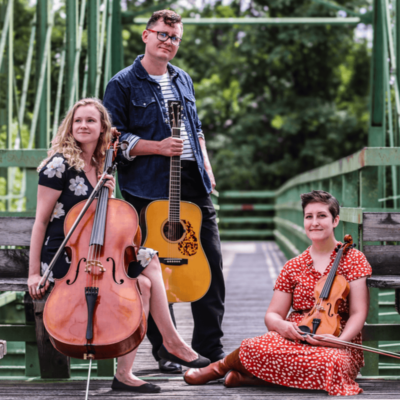 Ellen seated with cello, Gabriel standing with guitar, Dakota seated with fiddle.