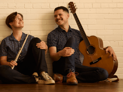 Grace Hendrickson-Jones and Everest Witman seated with flute and guitar.